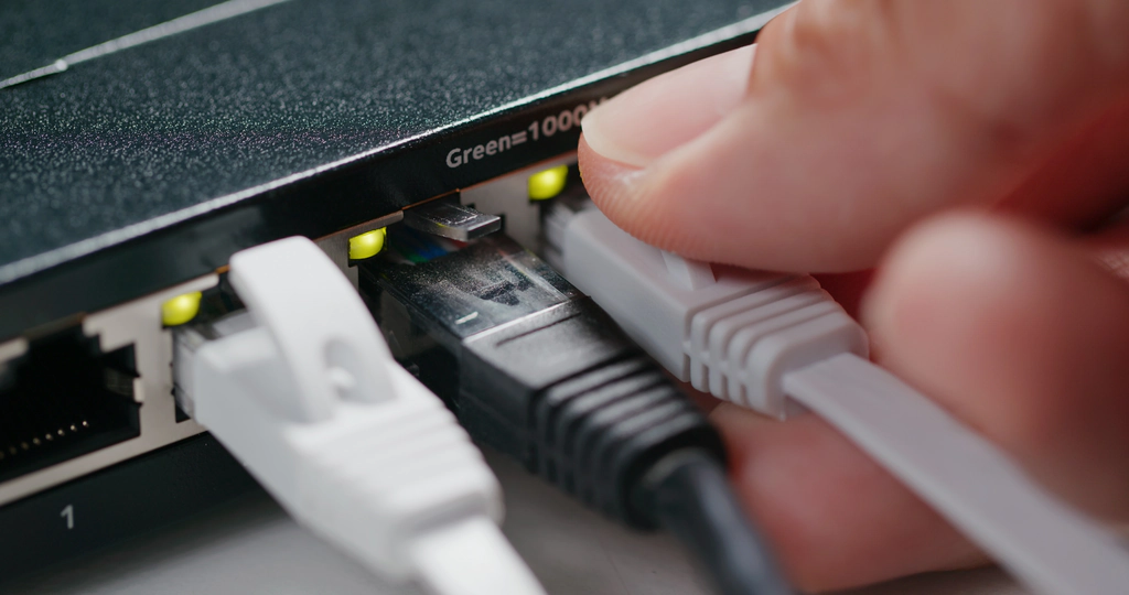 An IT professional pluging in a network cable into a switch